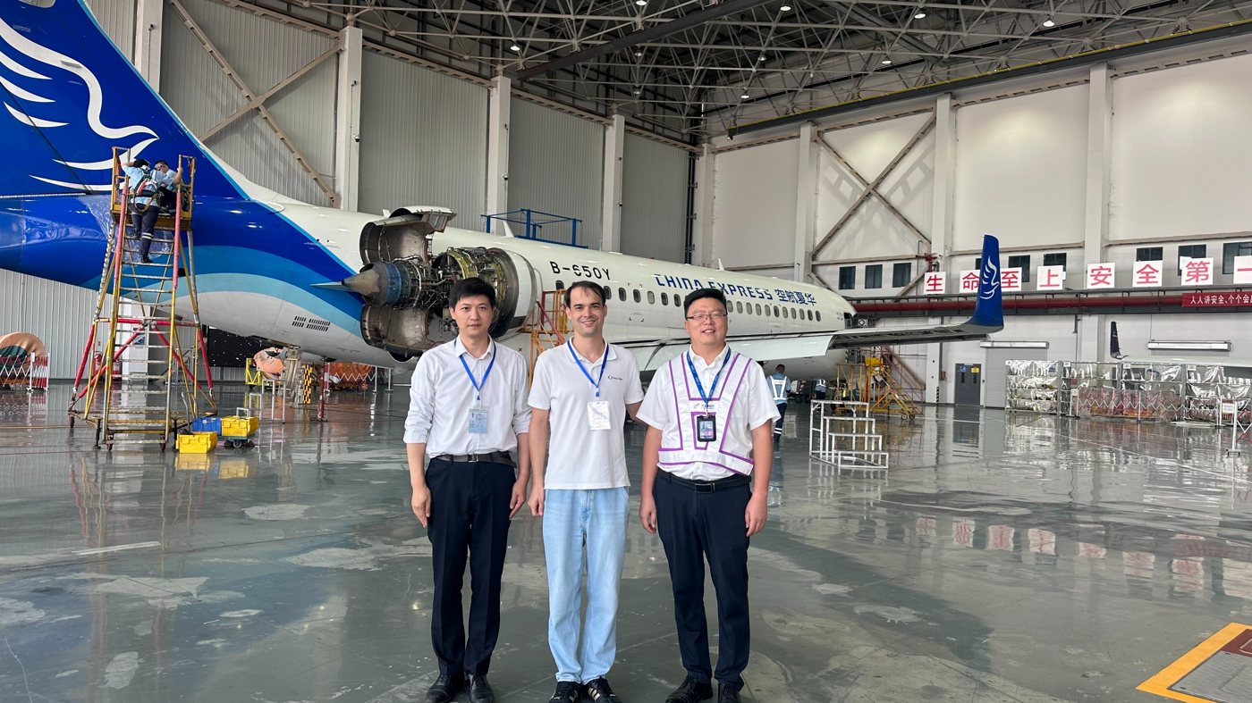 Technicians and visitors in a maintenance hangar with an aircraft on the floor