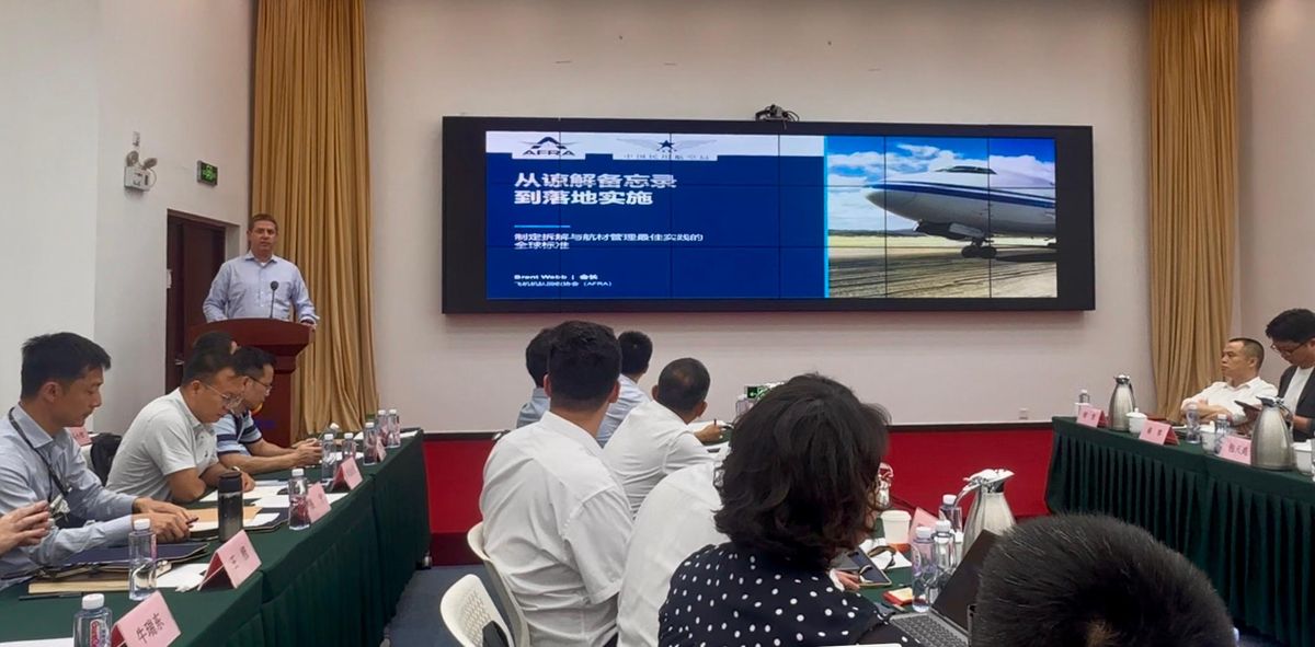 Brent Webb, President of AFRA, speaking at a lectern during the airline buyer-focused regulatory briefing in Beijing, with an AFRA presentation on a large screen behind him